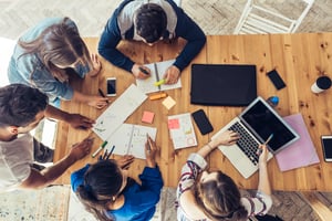 overhead view of 5 young marketers at a table, planning their strategy