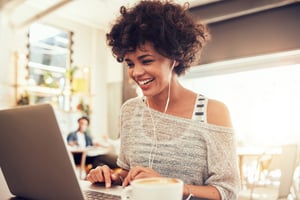 young woman wearing headphones and looking at her laptop